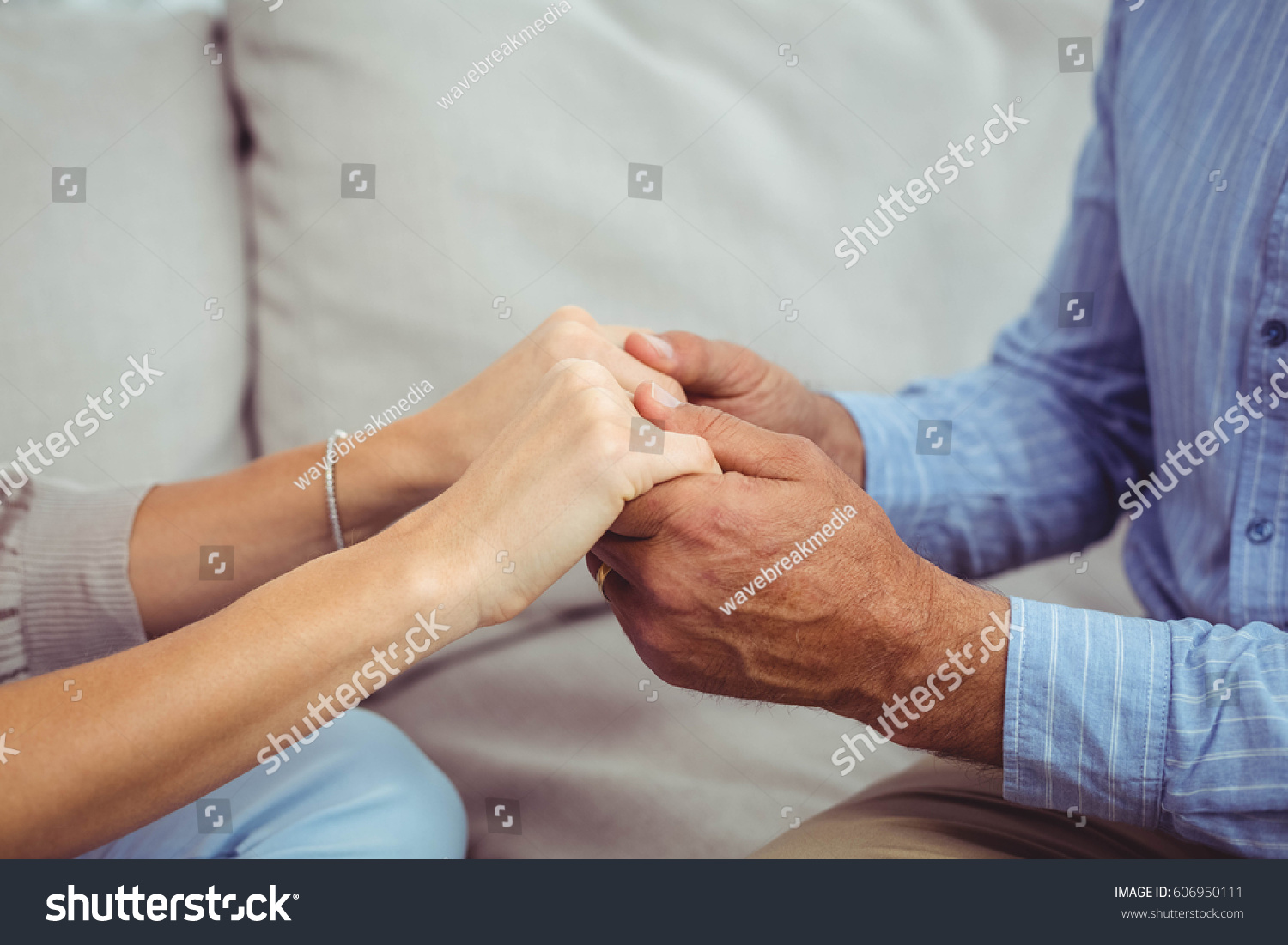 Close-up of man and woman holding hands at home #606950111