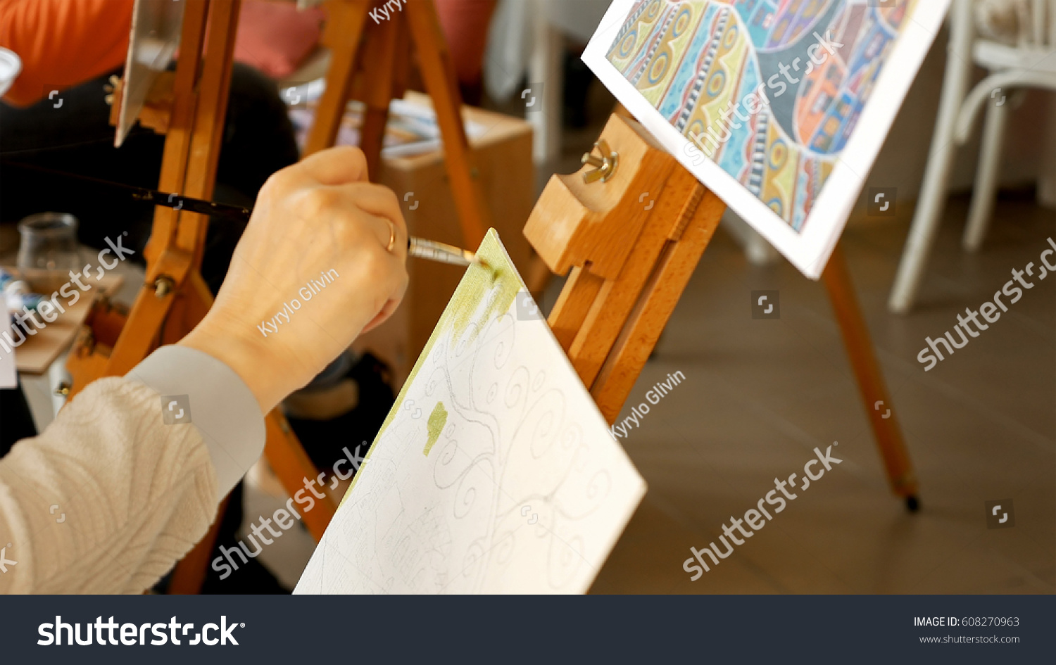 Female artist draws a pencil sketch drawing on canvas easel in art studio. Student girl learning to draw and paint. #608270963