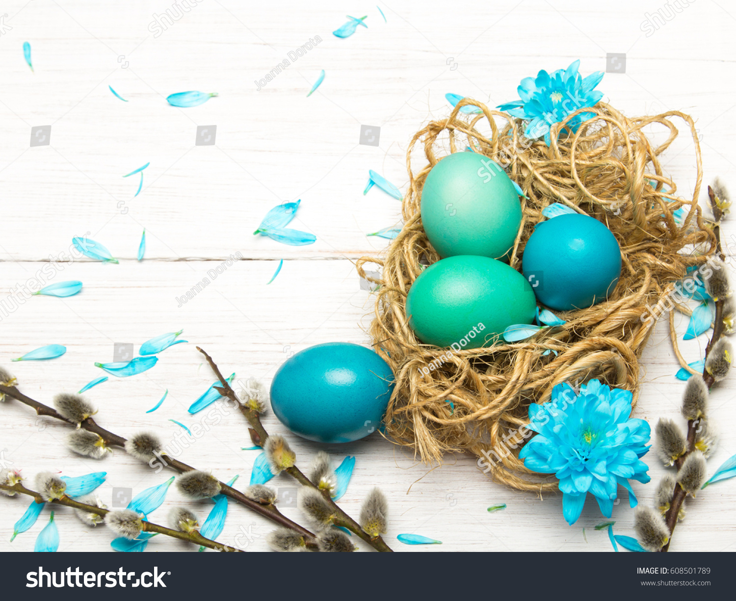 Easter background with eggs, nest and catkins on white wooden background, copy space #608501789