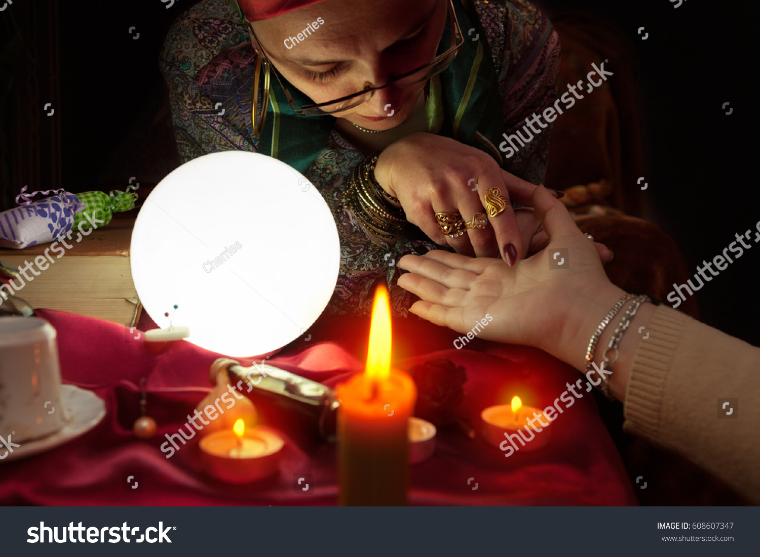 Old fortune teller woman holding another woman hand for palm reading #608607347