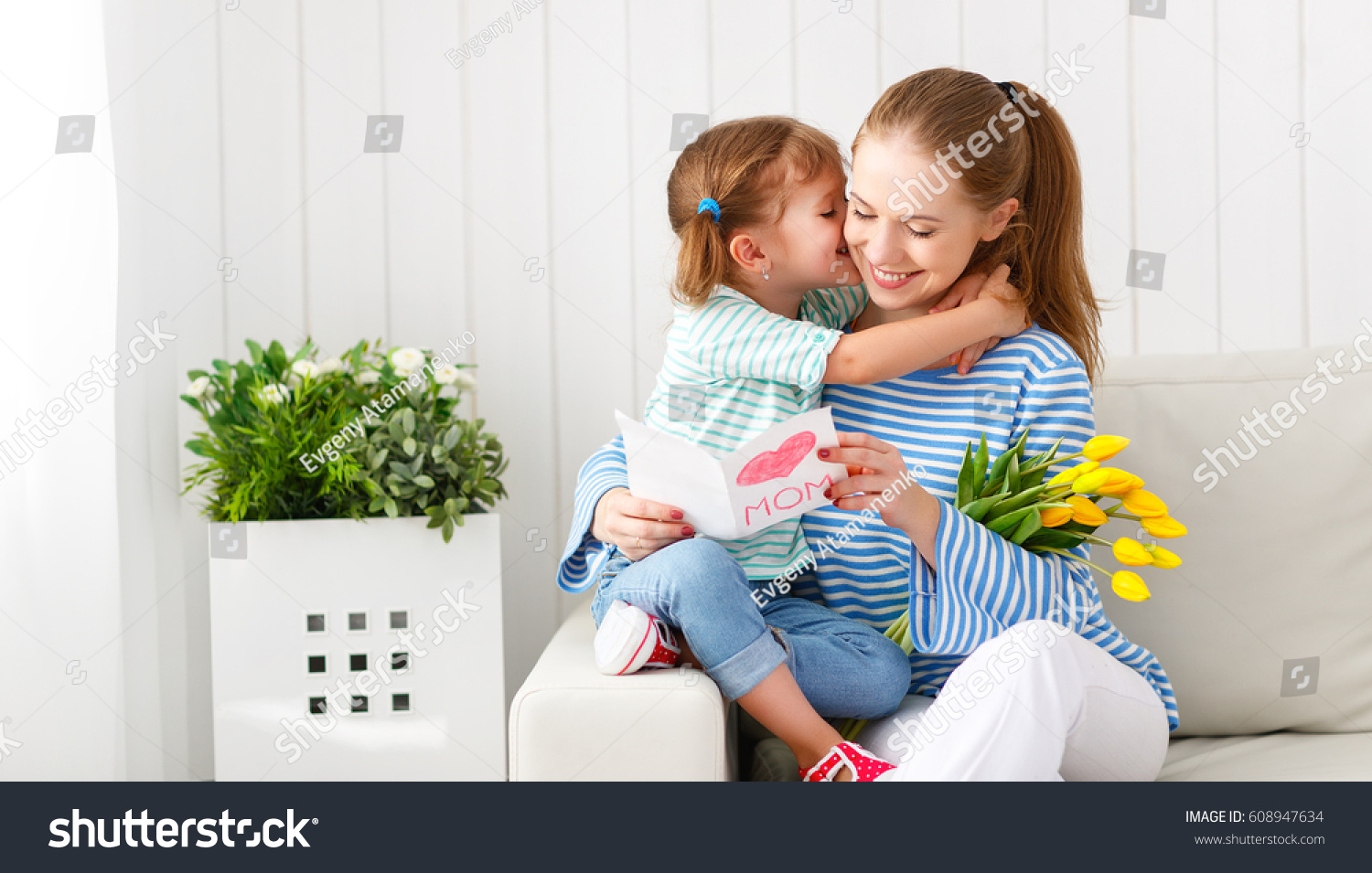 Happy mother's day! Child daughter congratulates moms and gives her a postcard and flowers tulips
 #608947634