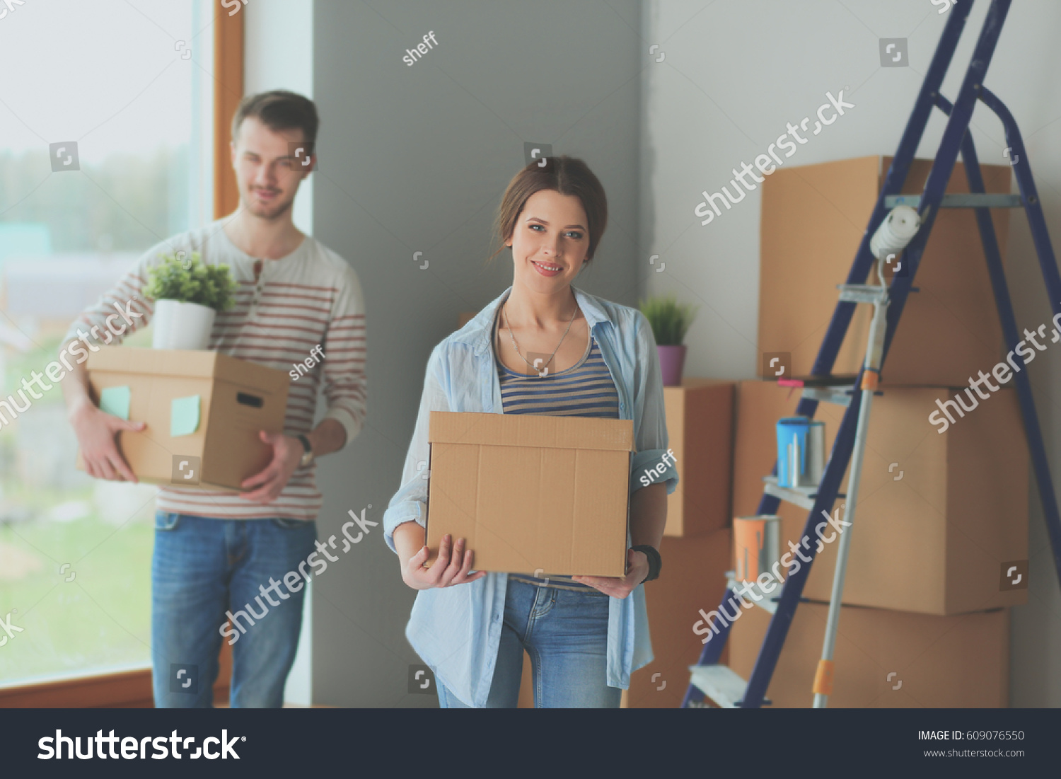 Happy young couple unpacking or packing boxes and moving into a new home #609076550