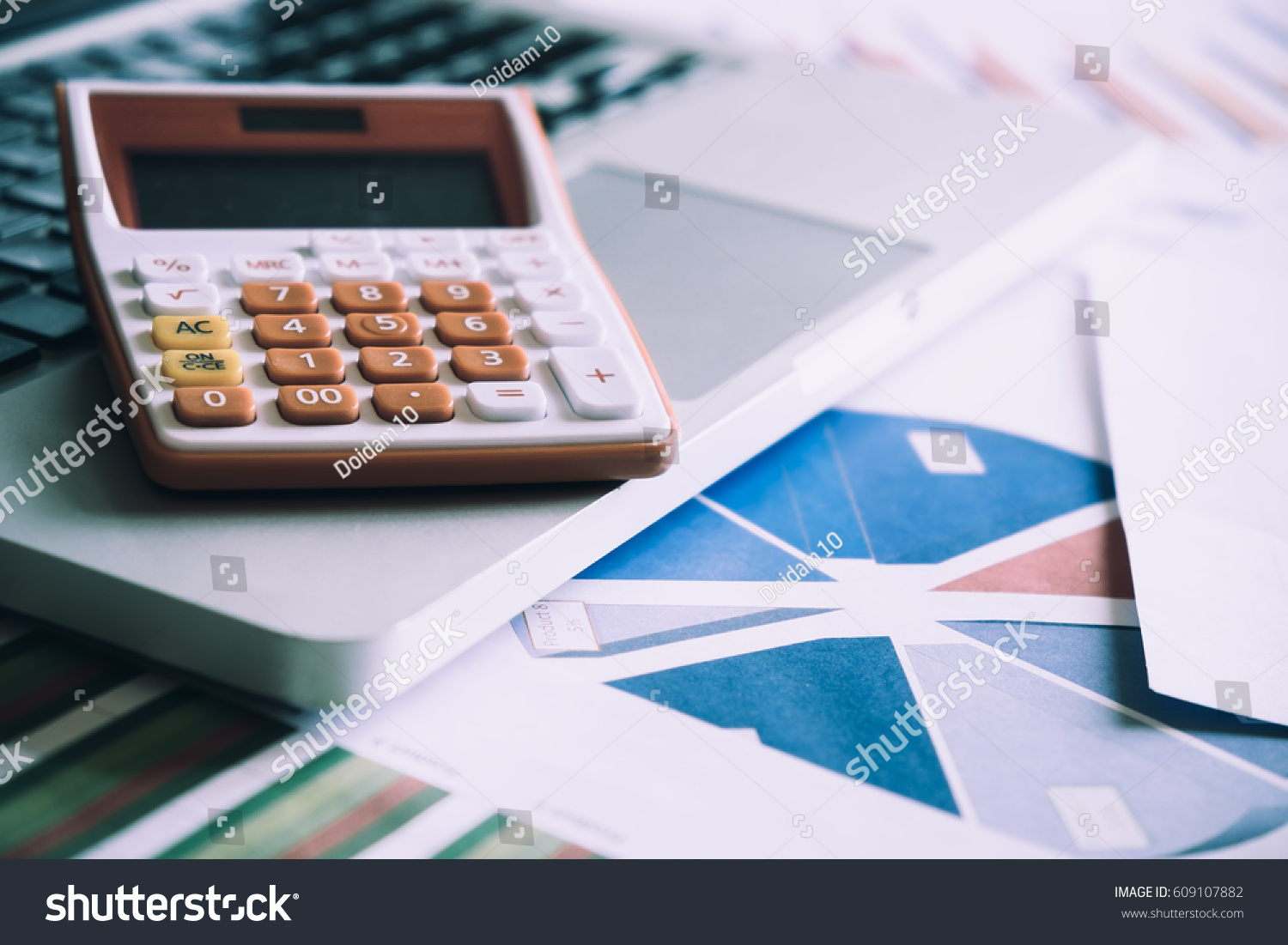 Calculator on a laptop keyboard with many charts and graphs. Reflection light and flare. Concept image of data gathering and statistical working.
 #609107882