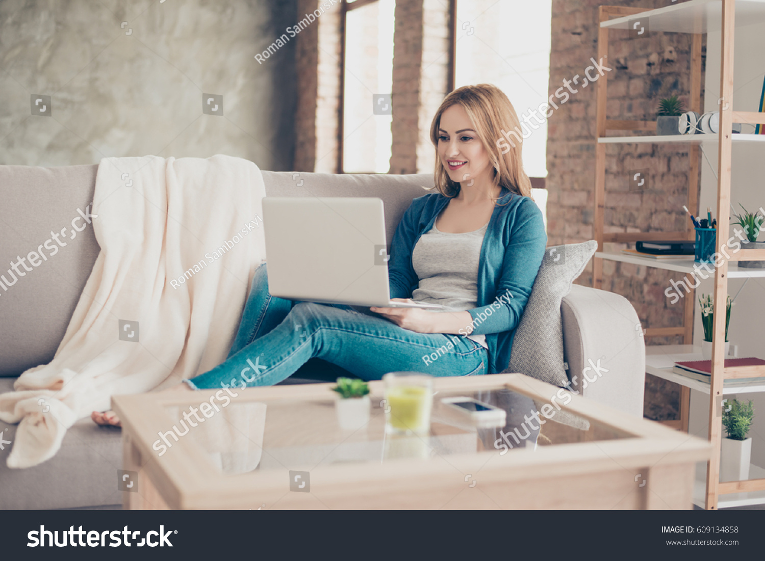Young pretty woman working with laptop sitting on the sofa. #609134858