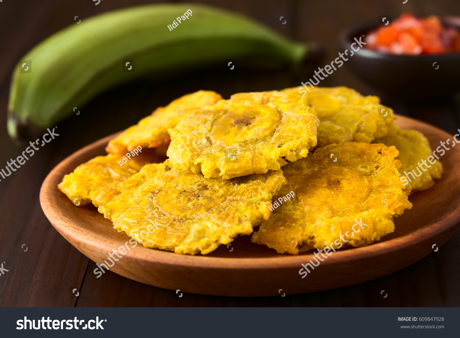 Patacon or toston, fried and flattened pieces of green plantain, traditional snack or accompaniment in the Caribbean, photographed with natural light (Selective Focus on the front of the top patacon)  #609847928