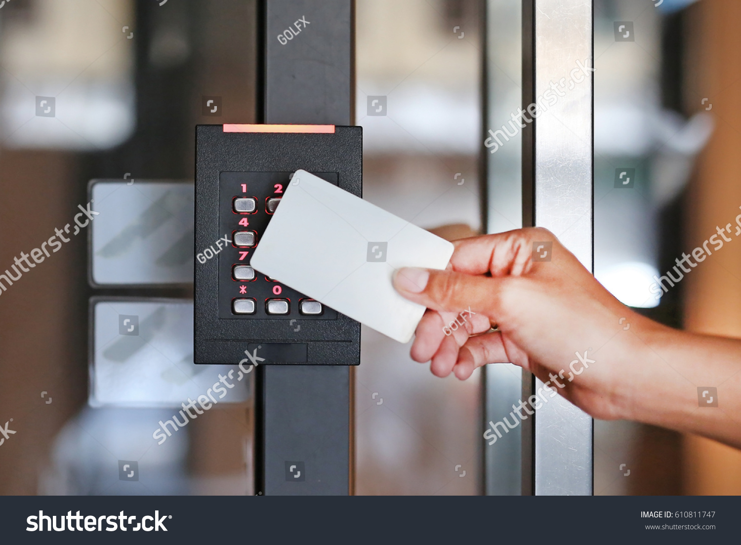 Door access control - young woman holding a key card to lock and unlock door. #610811747