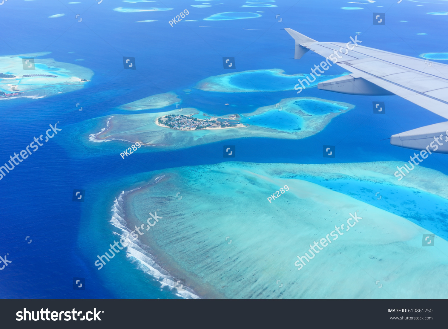 Scenery from airplane 's window seeing wing of airplane , white clouds , blue sky and Maldives islands  #610861250