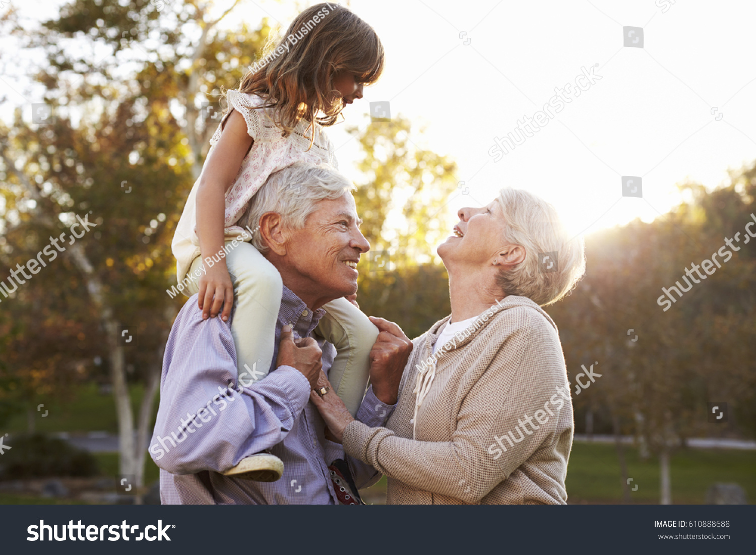 Grandparents Giving Granddaughter A Shoulder Ride In Park #610888688