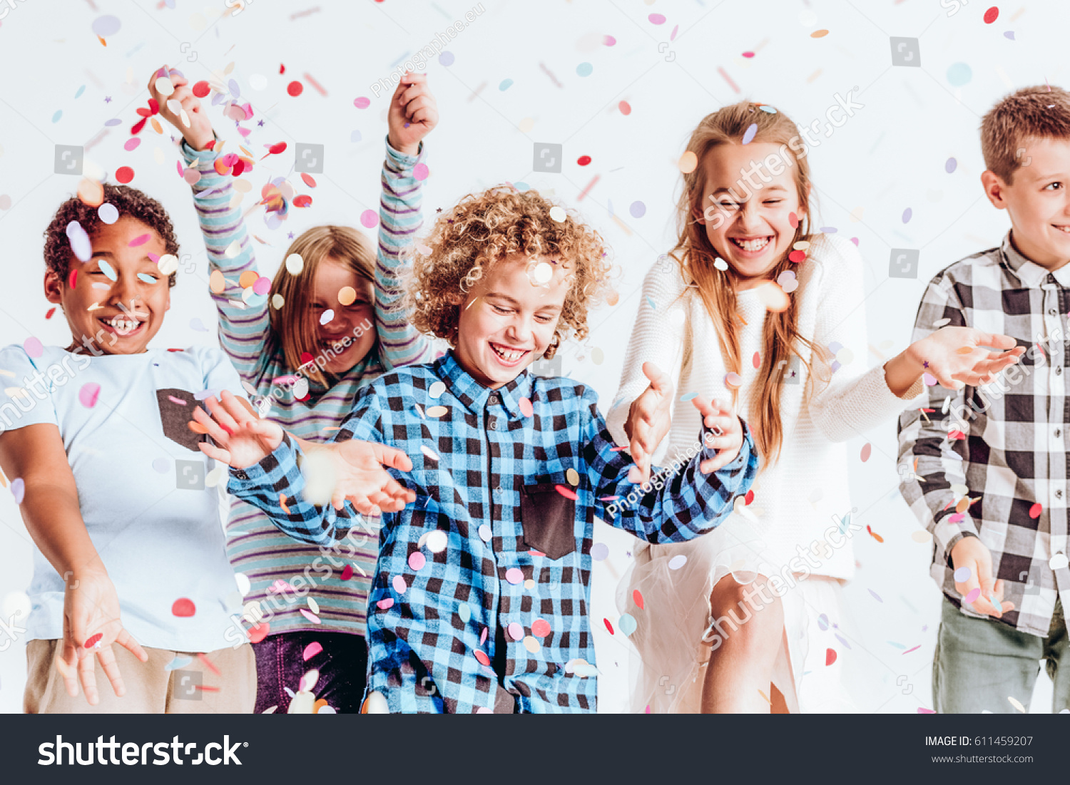 Happy kids throwing colorful confetti in a room #611459207