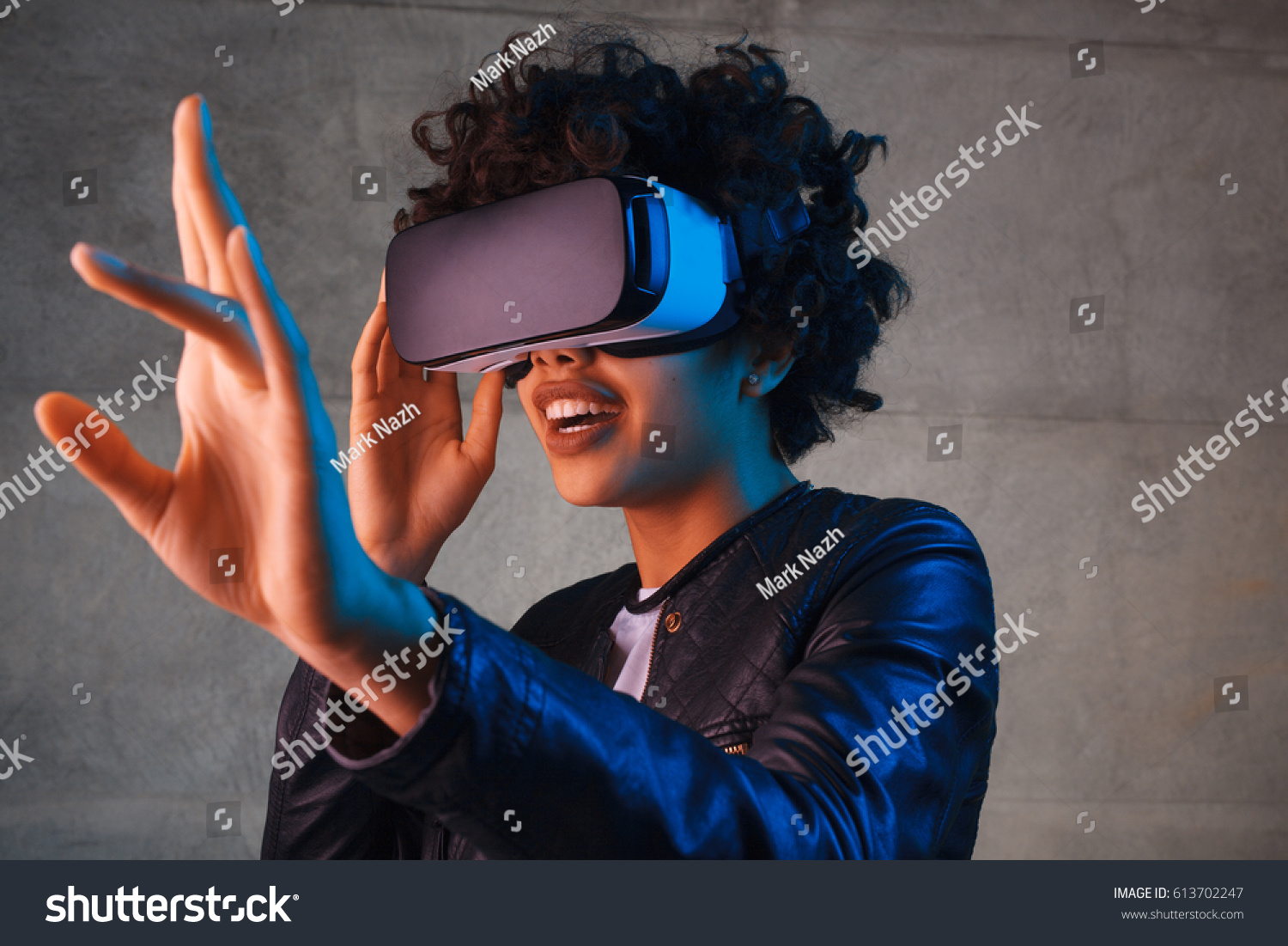 Amazed young woman touching the air during the VR experience. Horizontal studio shot. #613702247