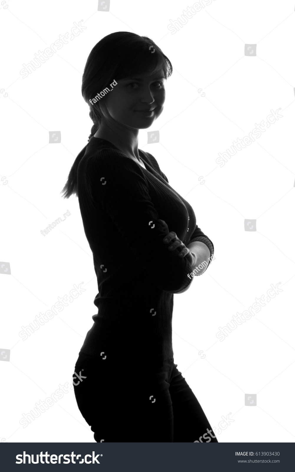 Black and white silhouette portrait of a young confident female with her arms folded over her chest #613903430