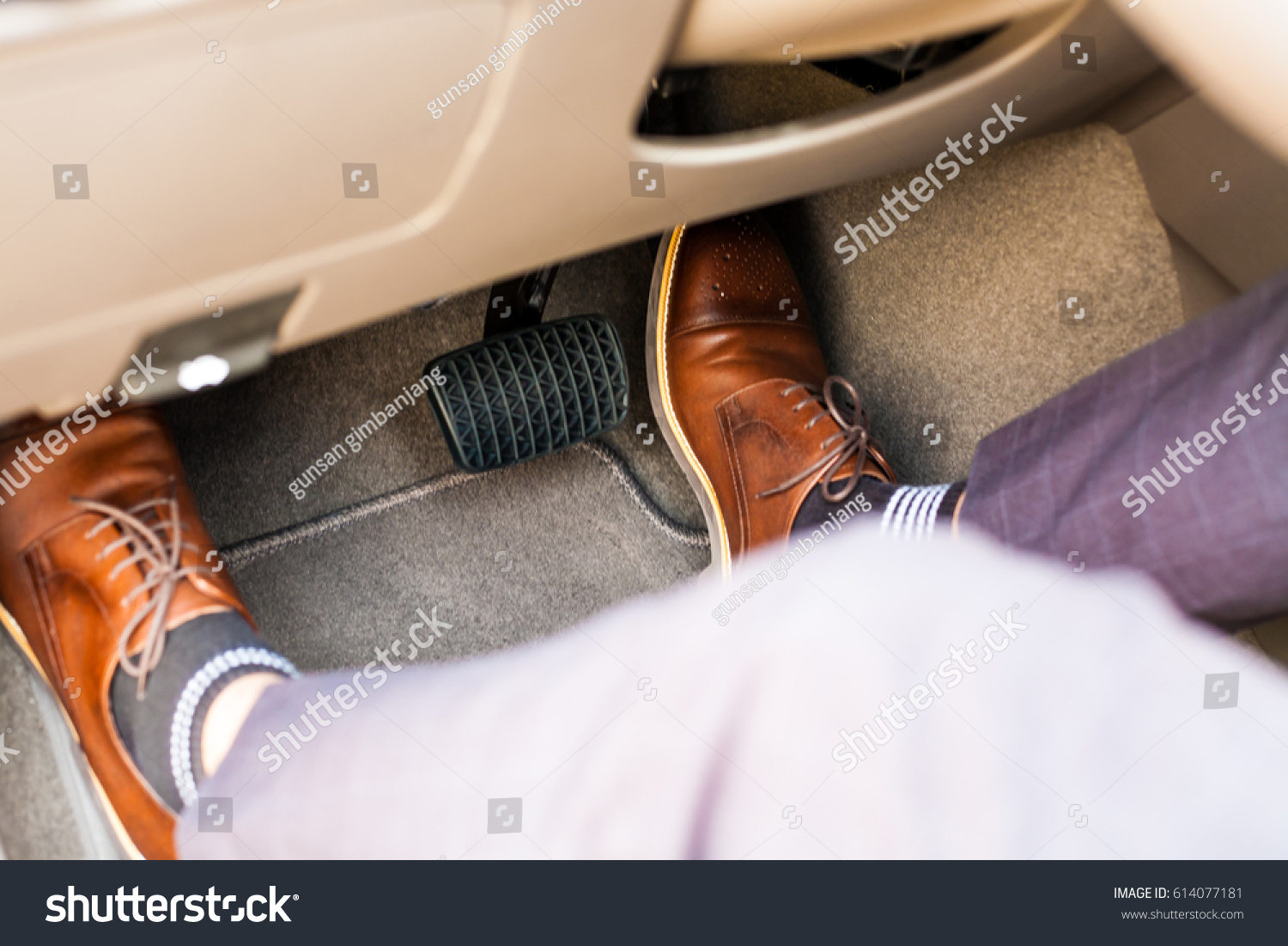 Closeup of a thirties man wearing brown shoes carrying a car accelerator and a brake / car safety system on the feet Accident and brake, danger of auto motor-driven bikes, driving habits #614077181