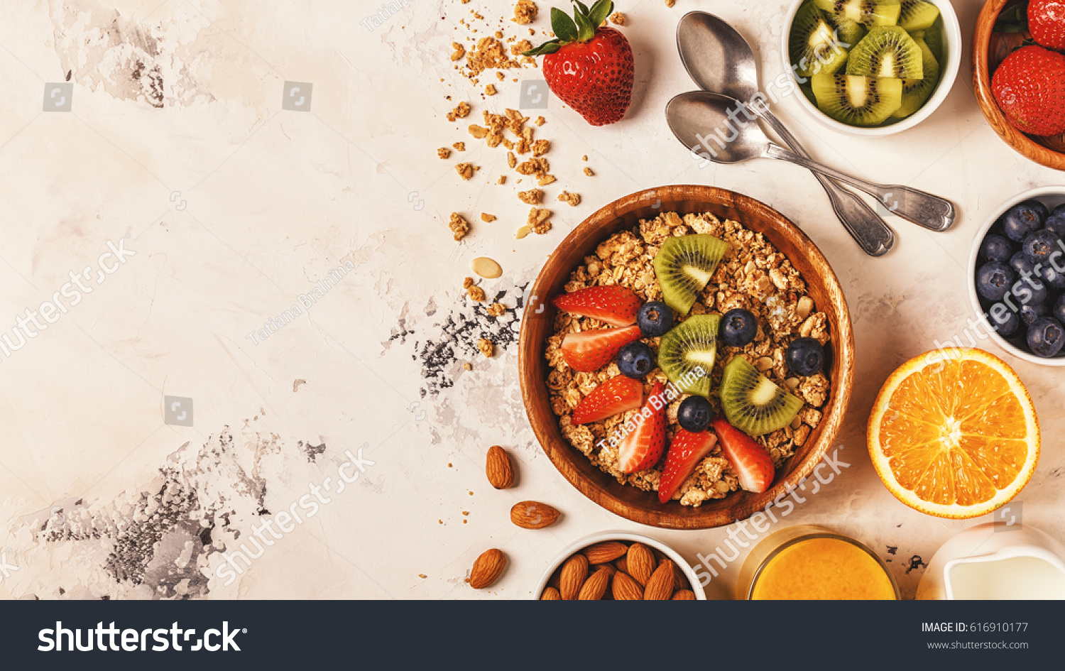 Healthy breakfast - bowl of muesli, berries and fruit, nuts, orange juice, milk, top view. #616910177