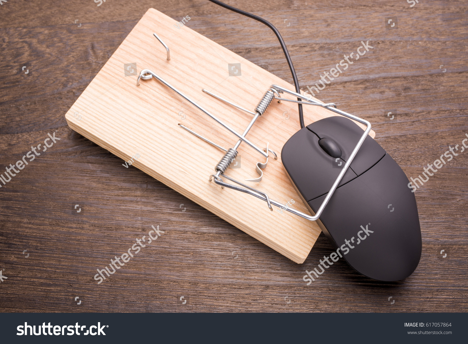 Computer mouse caught by the mousetrap device on wooden table #617057864