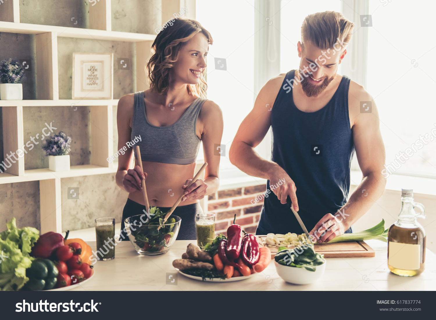 Beautiful young sports people are talking and smiling while cooking healthy food in kitchen at home #617837774