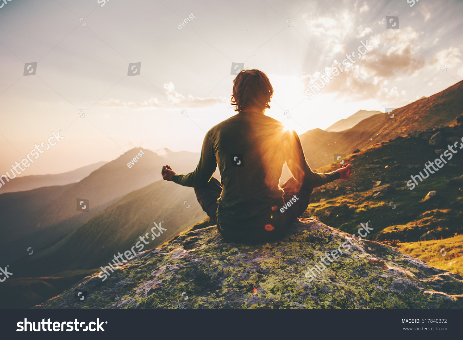 Man meditating yoga at sunset mountains Travel Lifestyle relaxation emotional concept adventure summer vacations outdoor harmony with nature #617840372