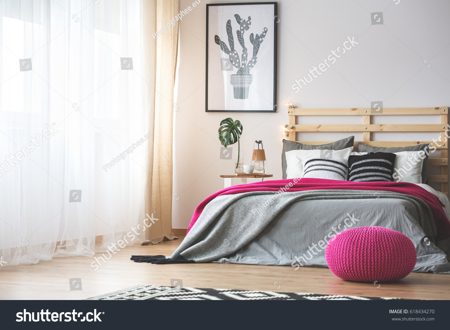 King-size bed in bright bedroom with pink accessories #618434270