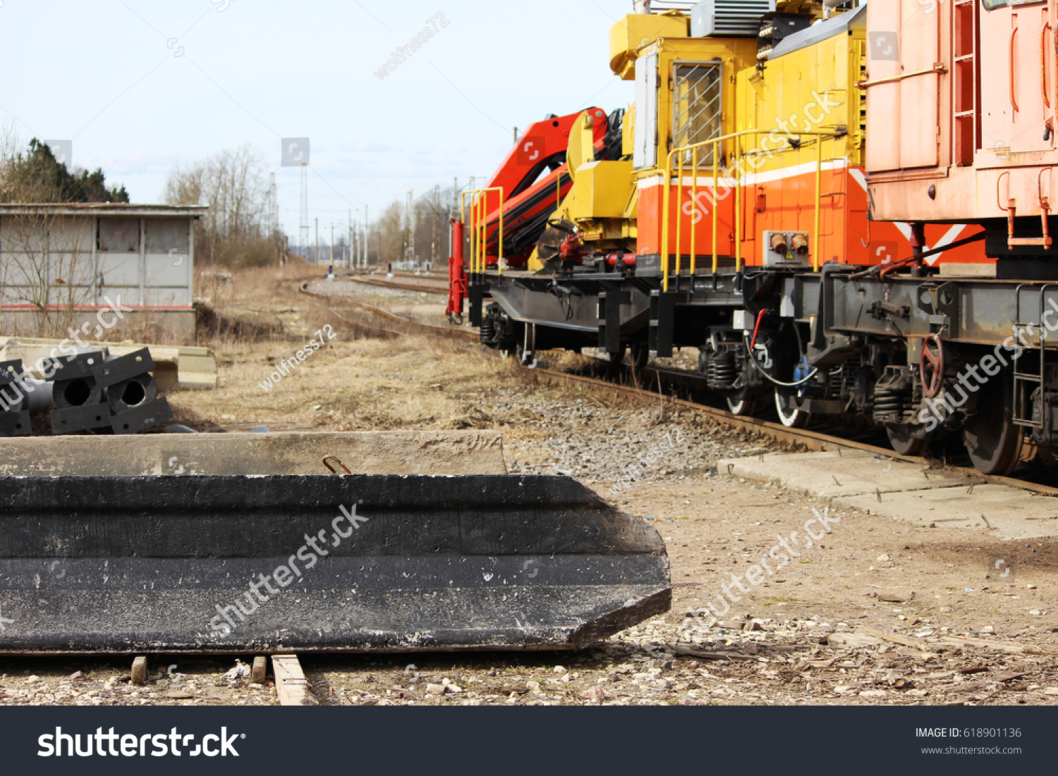 Reinforced concrete piles lie on the ground after unloading with a loader on the railway. #618901136