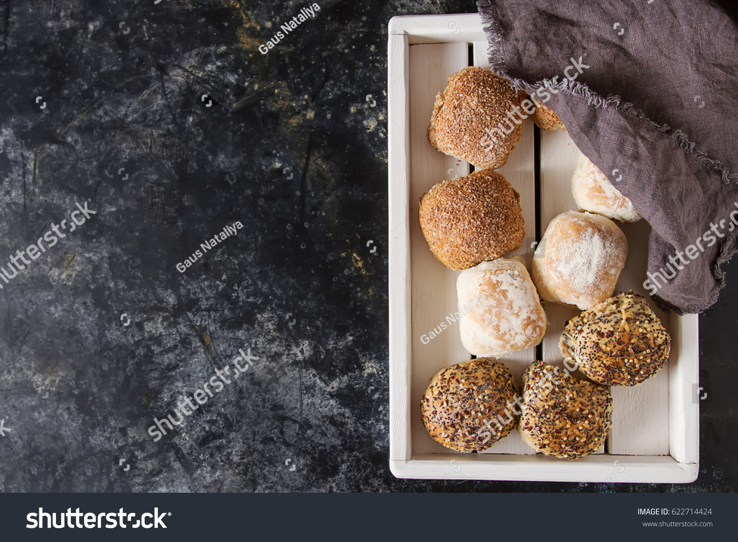 Fresh homemade bread from wheat. Dark background. A wooden tray. Top view. Copy space. Selective focus. The concept of a healthy diet or dietary nutrition #622714424