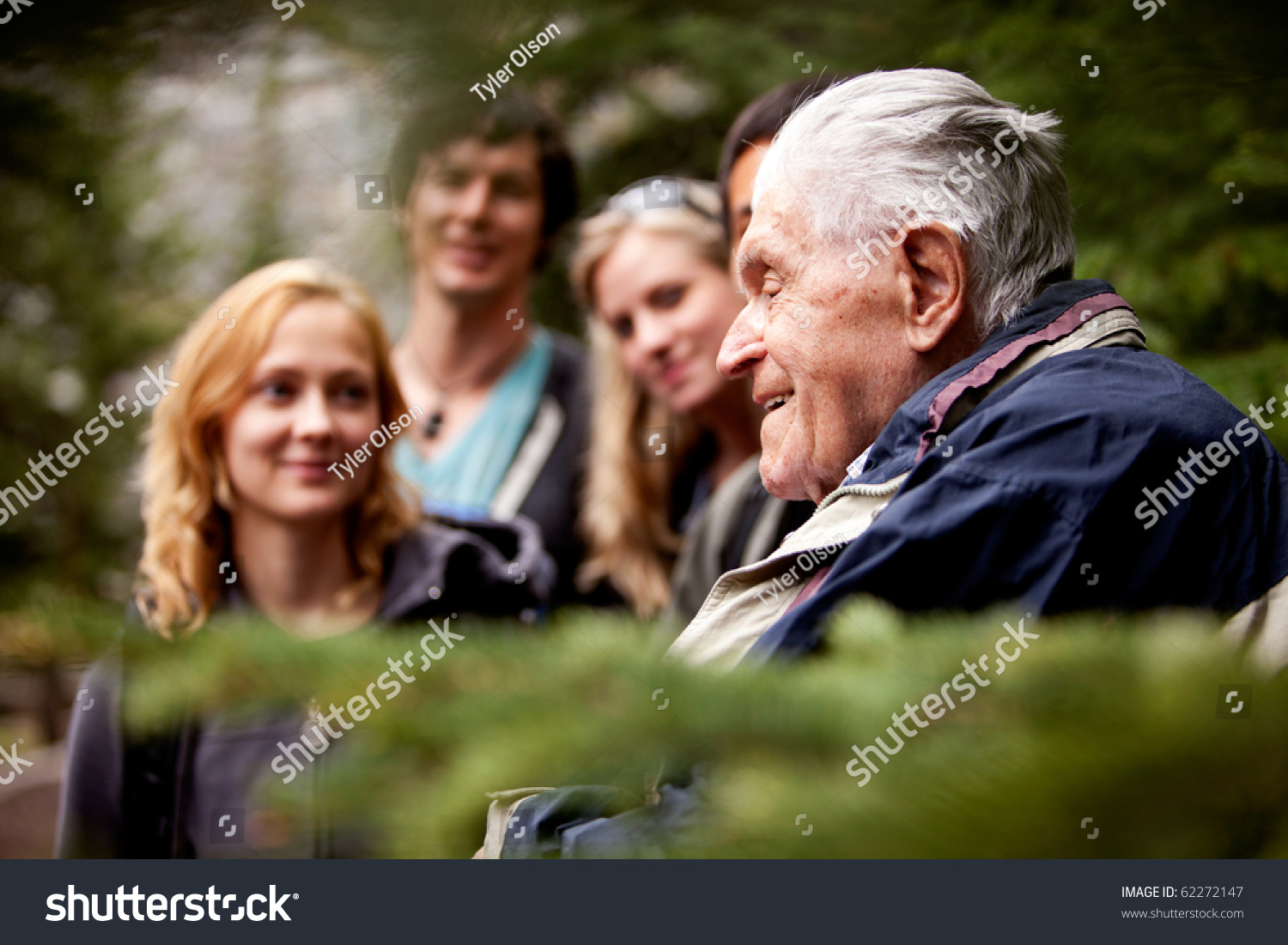 An elderly man telling stories to a group of young people #62272147