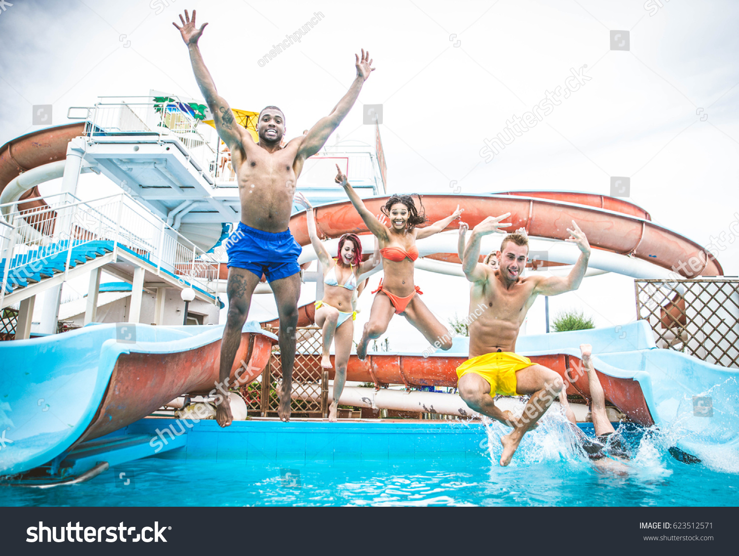 Multi-ethnic group of friends in a swimming pool - Young happy people having fun and enjoying summertime in a aquapark #623512571