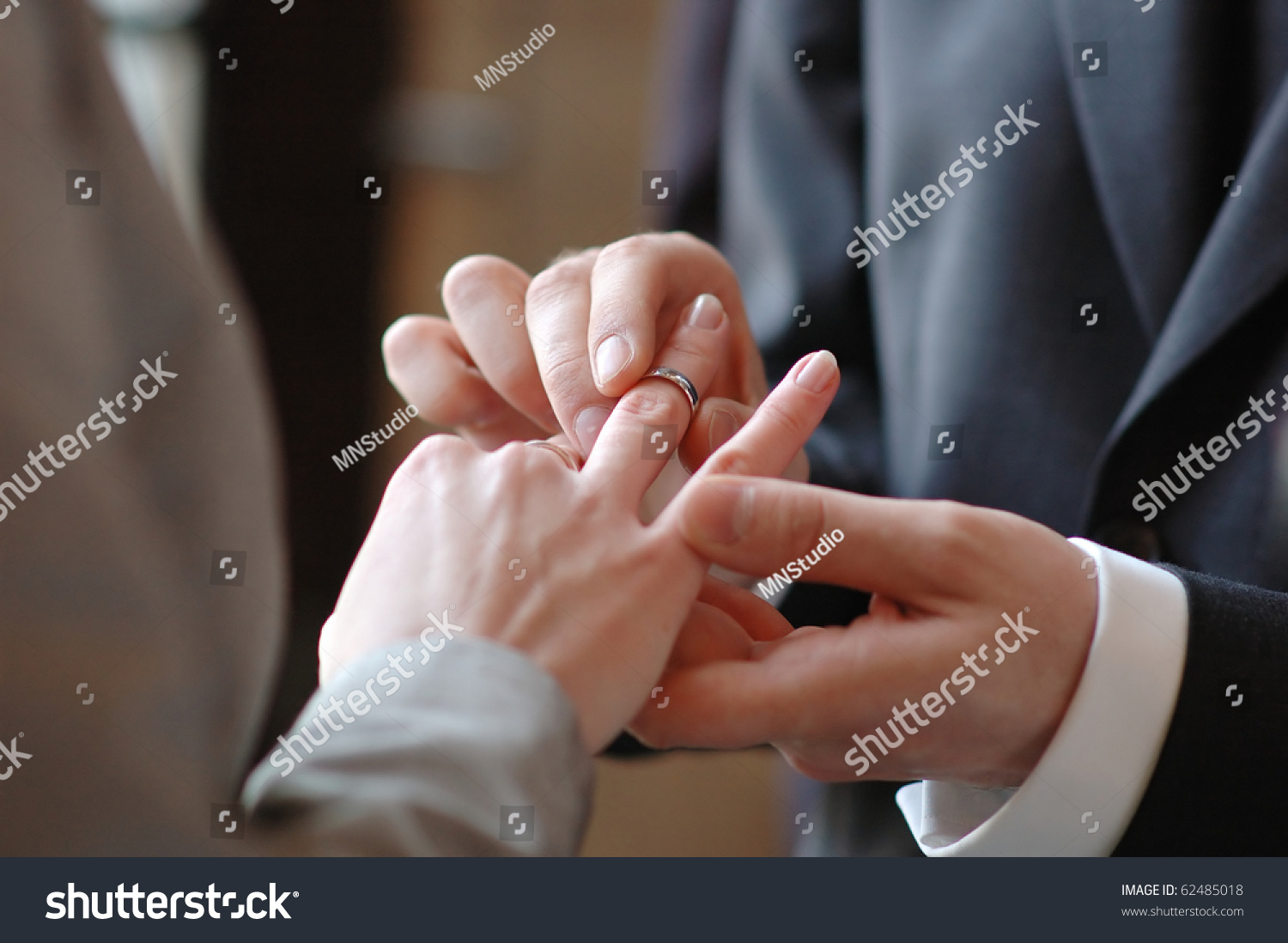 Groom putting a wedding ring on bride's finger #62485018