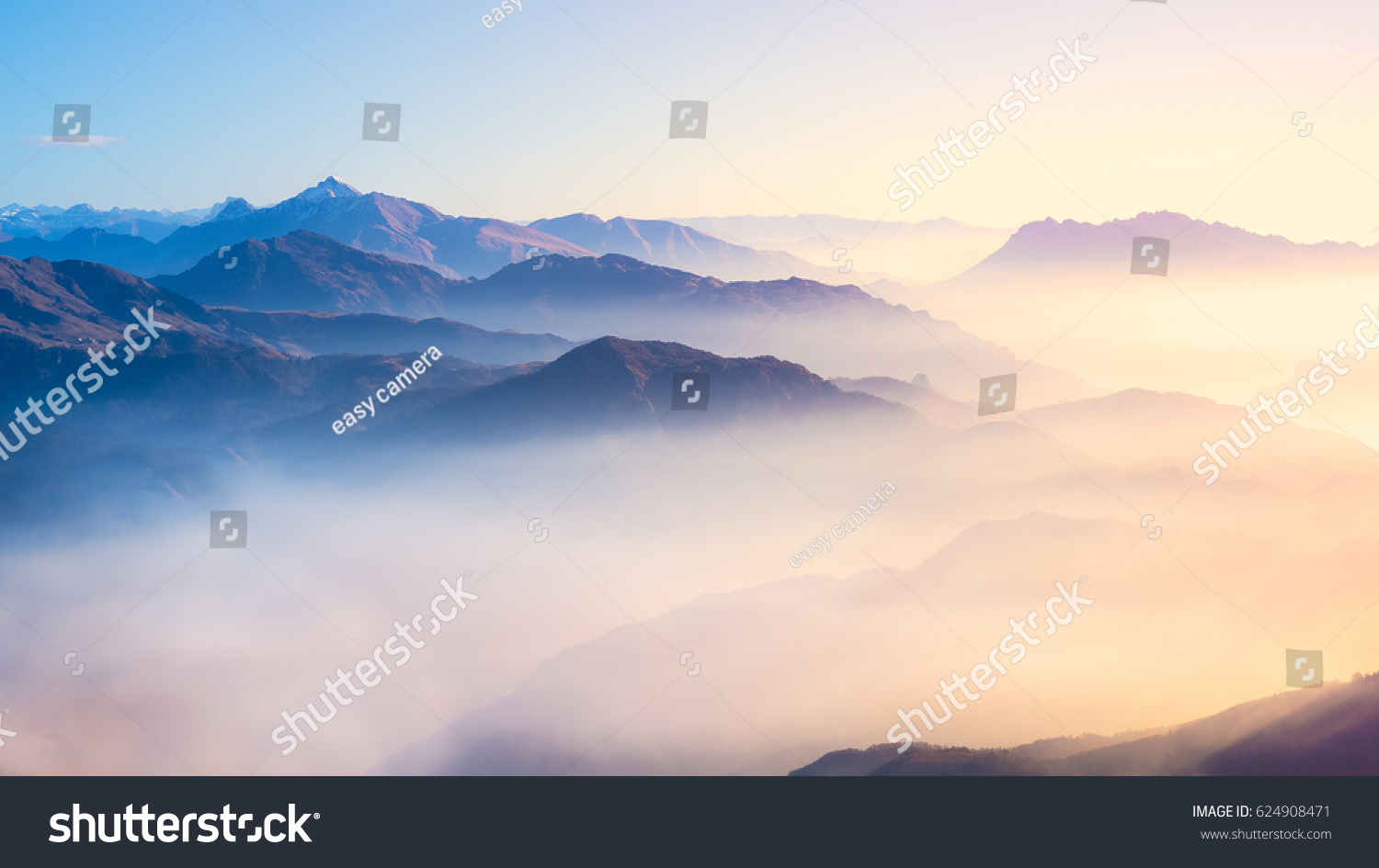 Mountain range with visible silhouettes through the morning colorful fog. #624908471
