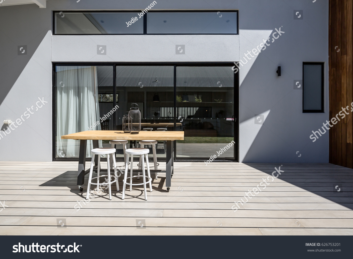Sunny outdoor entertaining deck with triple glass sliding doors #626753201