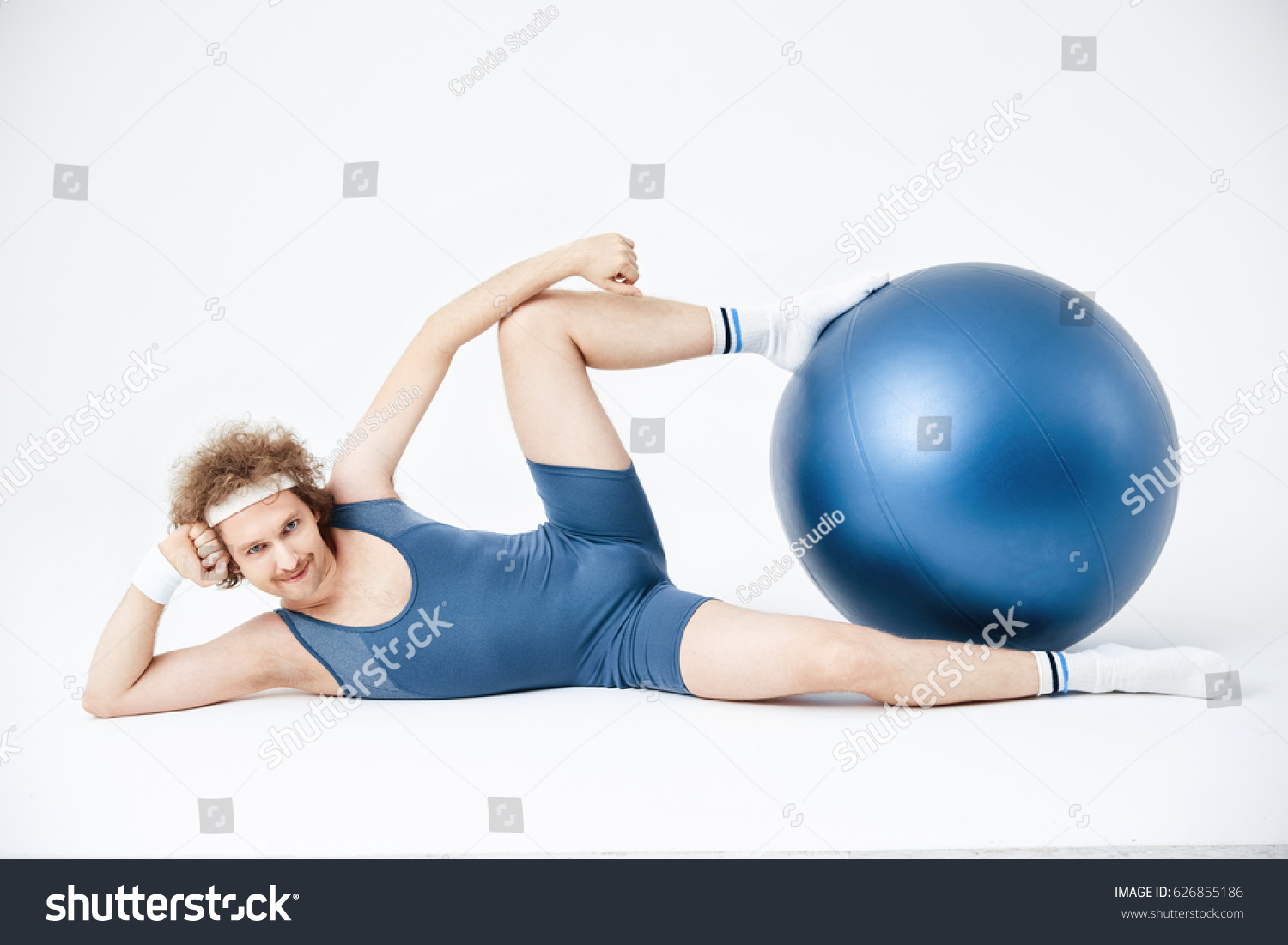 Man posing lying on floor, holding exercise ball with legs #626855186