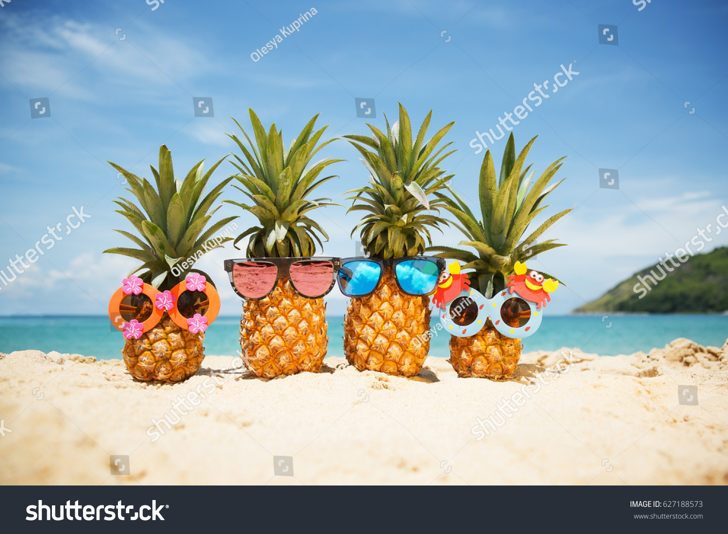 Family of funny attractive pineapples in stylish sunglasses on the sand against turquoise sea. Tropical summer vacation concept. Happy sunny day on the beach of tropical island. Family holiday #627188573