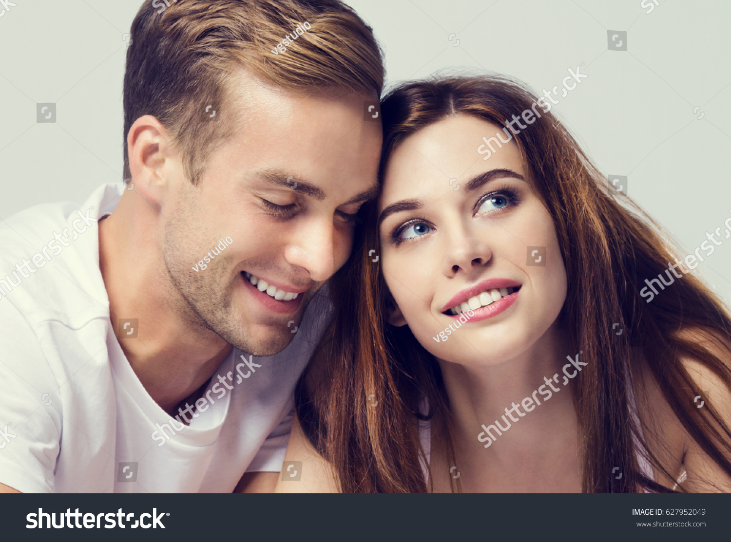 Young couple, looking at you. Caucasian models - love, relationship, dating, happy lovers, concept shot, against grey, with copyspace for slogan or text message.  Horizontal banner composition. #627952049