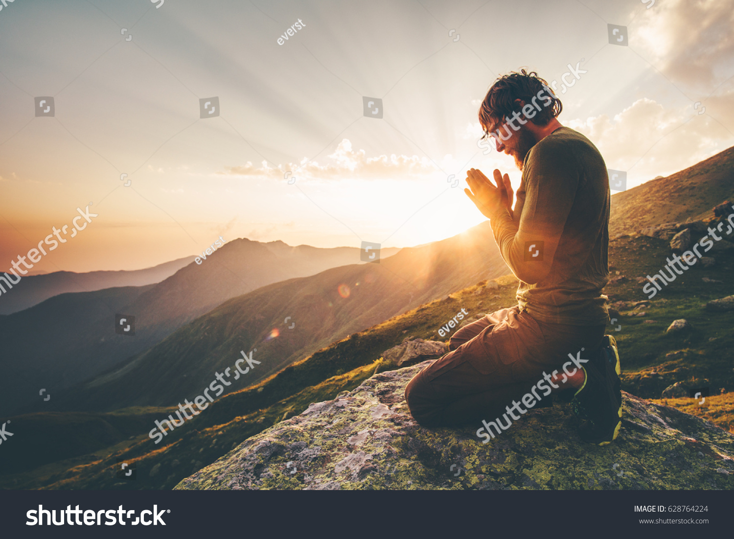 Man praying alone at sunset mountains Travel Lifestyle spiritual relaxation emotional concept vacations outdoor harmony with nature landscape #628764224