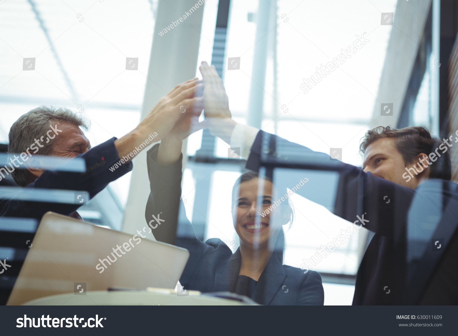 Businesspeople giving a high five to each other in office #630011609