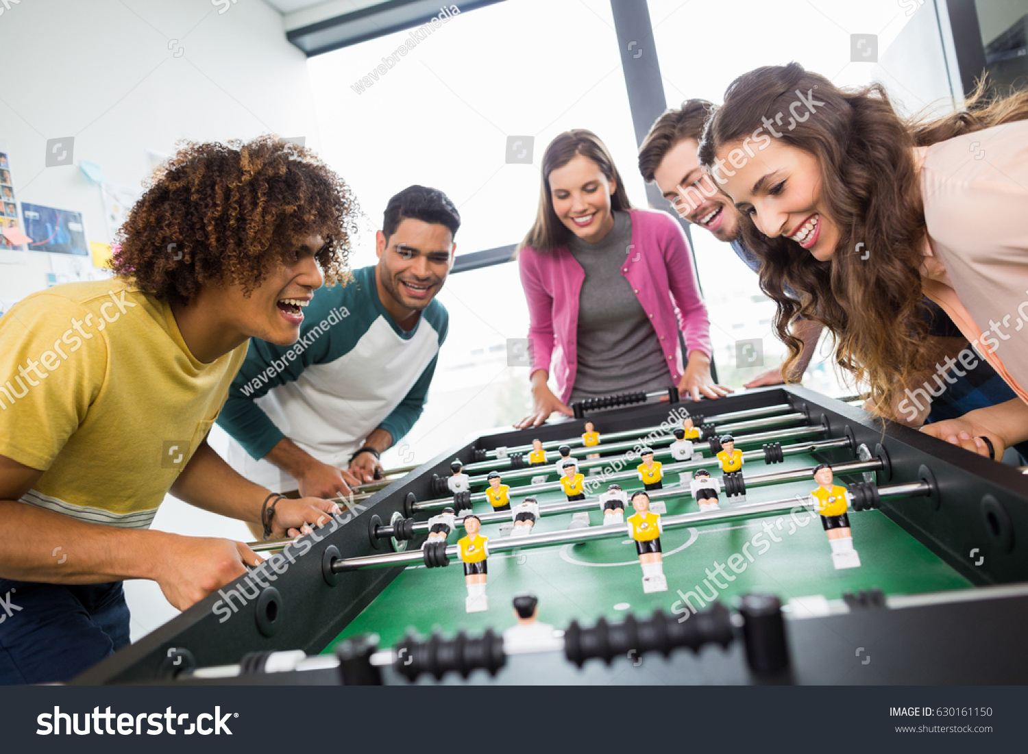Happy executives playing table football in office #630161150