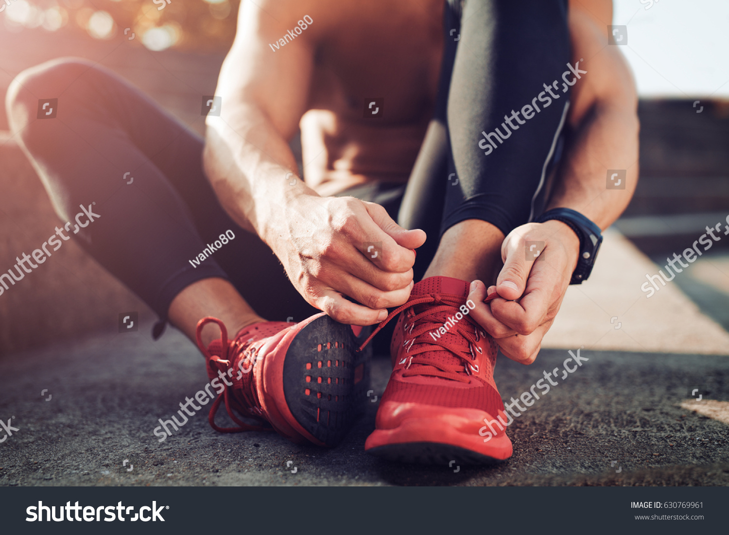 Man tying jogging shoes.A person running outdoors on a sunny day. #630769961