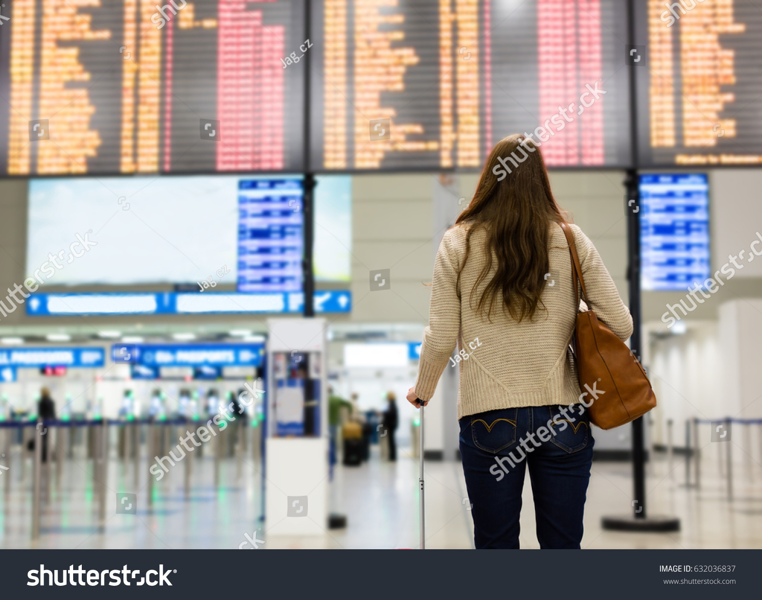 Young woman looking at the flight information board on the airport, checking her flight #632036837