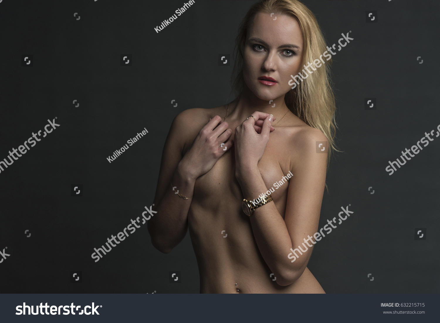 Blonde in blue jeans covers her bare chest with her hands #632215715