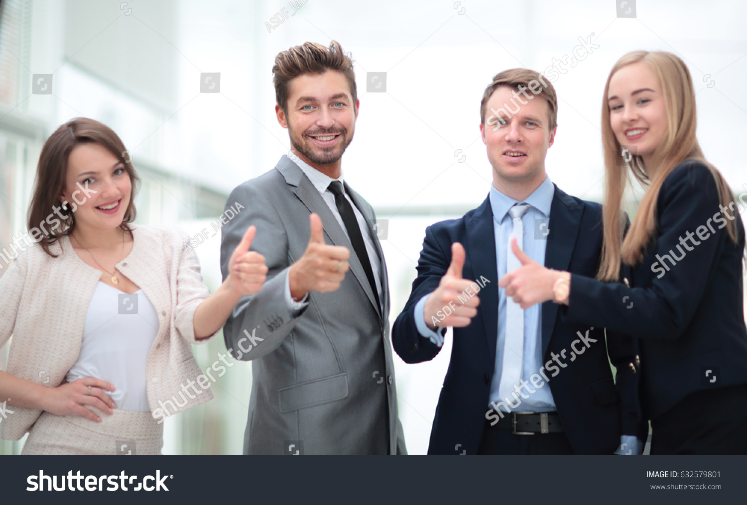 Business colleagues looking at camera and shoving thumbs up in t #632579801