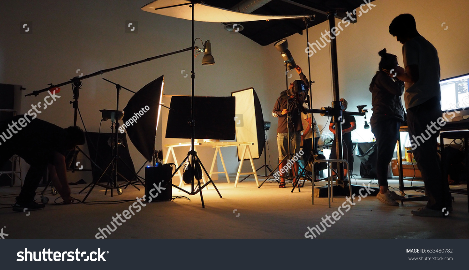 Behind the shooting production crew team and silhouette of camera and equipment in studio.
