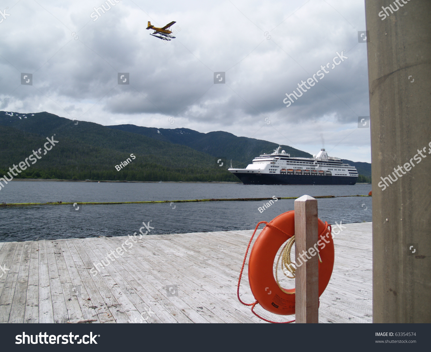 Float plane flys above incoming cruise ship with Ketchican pier and lifesaver in foreground. #63354574