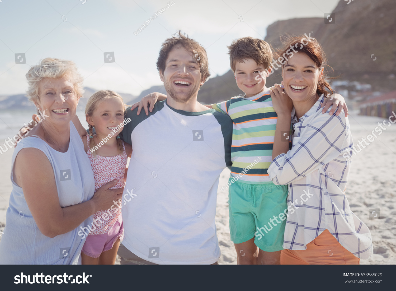 Portrait of multi-generated family embracing at beach during sunny day #633585029