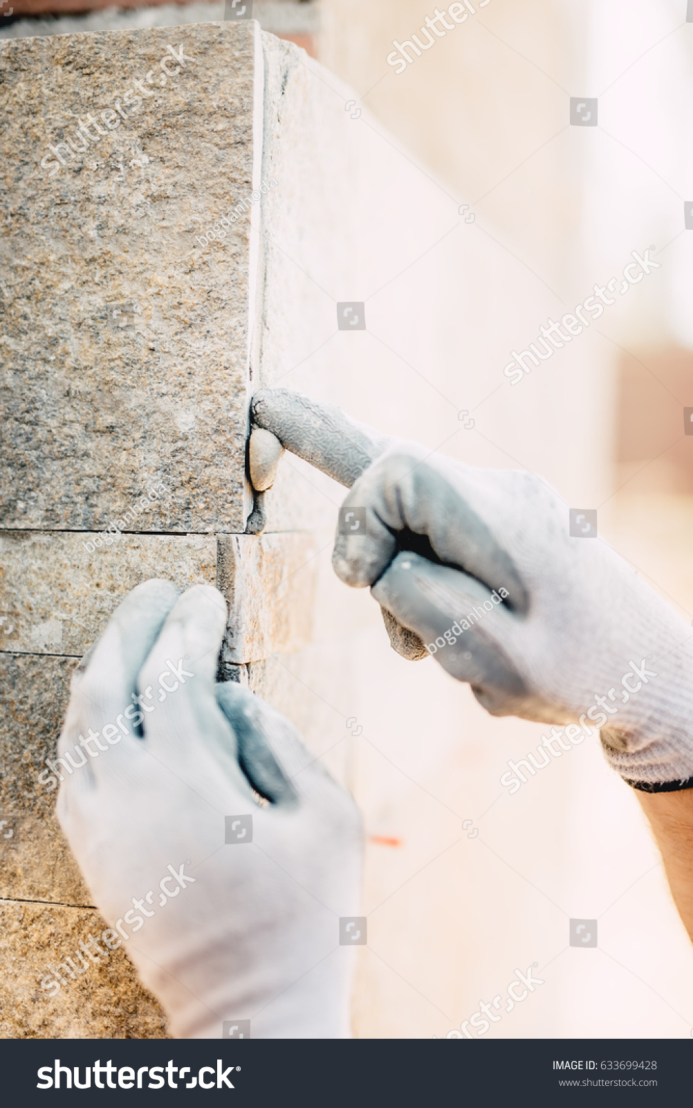close up details of worker hands plastering and installing stone on construction site. perfection details in construction industry #633699428