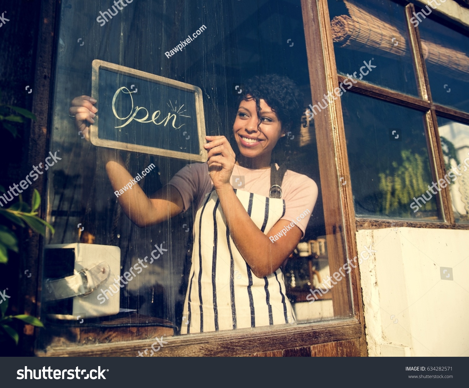 Woman Hanging Open Sign by the Glass Window #634282571