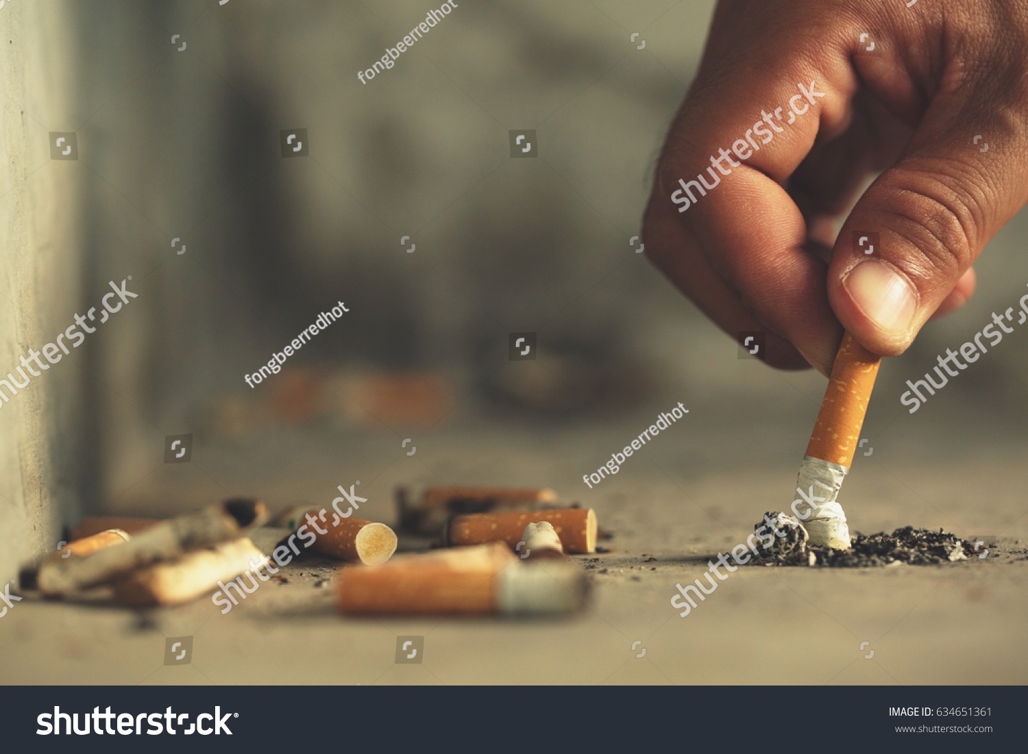 Hand putting out a cigarette,cigarette butt on Concrete floor, bare cement. #634651361