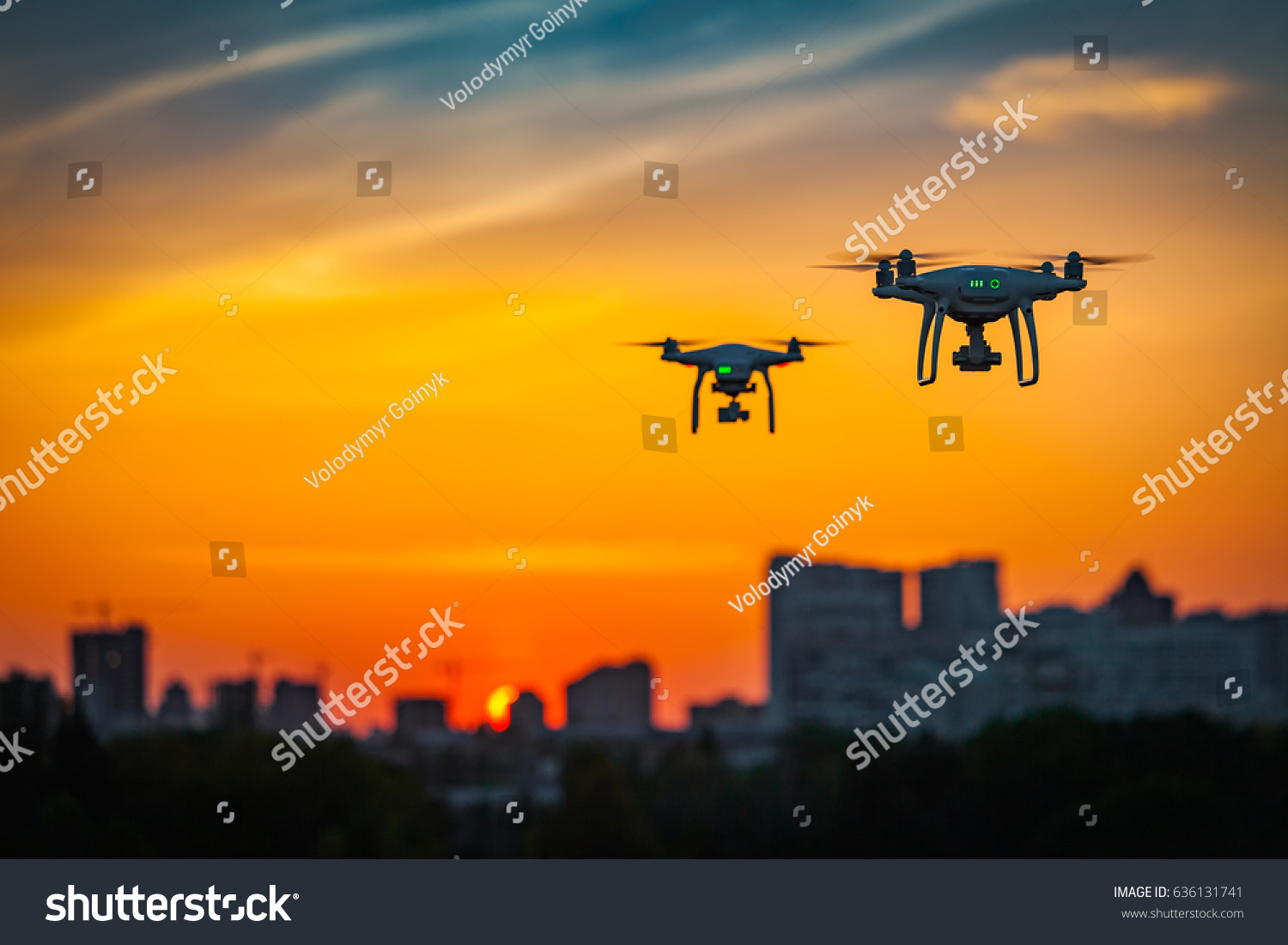 Two drone quad copters with high resolution digital camera flying aerial over spectacular sunset orange sky. Cityscape silhouette with sun goes down in the background.Vehicle at sundown and copy space #636131741