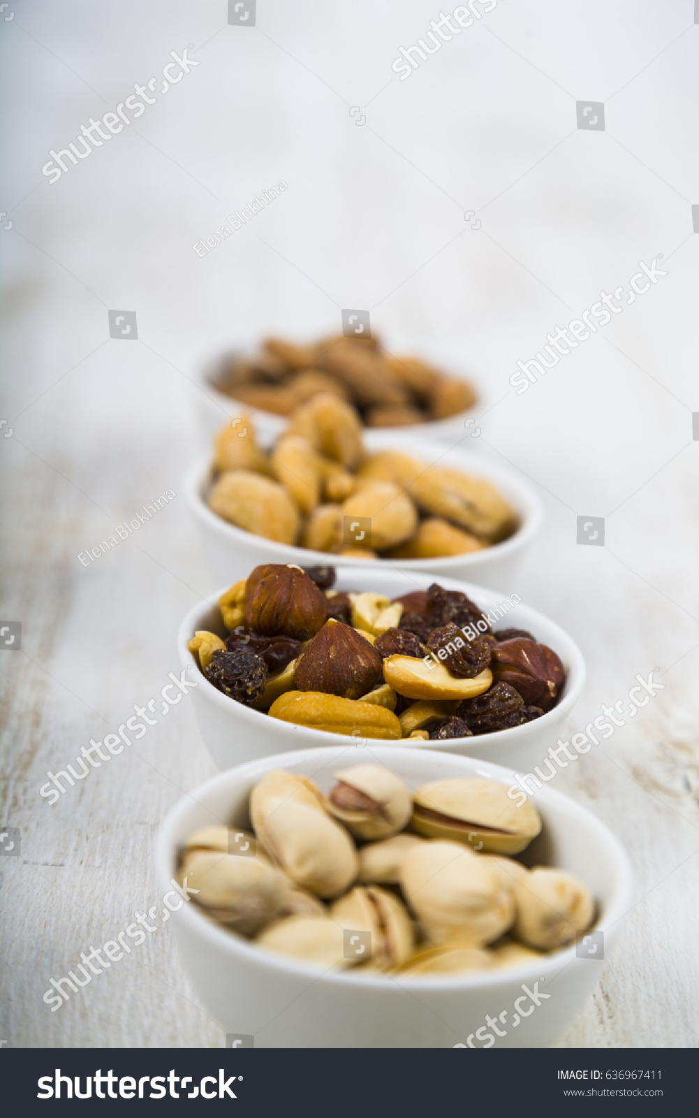 Nuts in a plate on a  wooden table. Different kinds of tasty and healthy nuts. #636967411