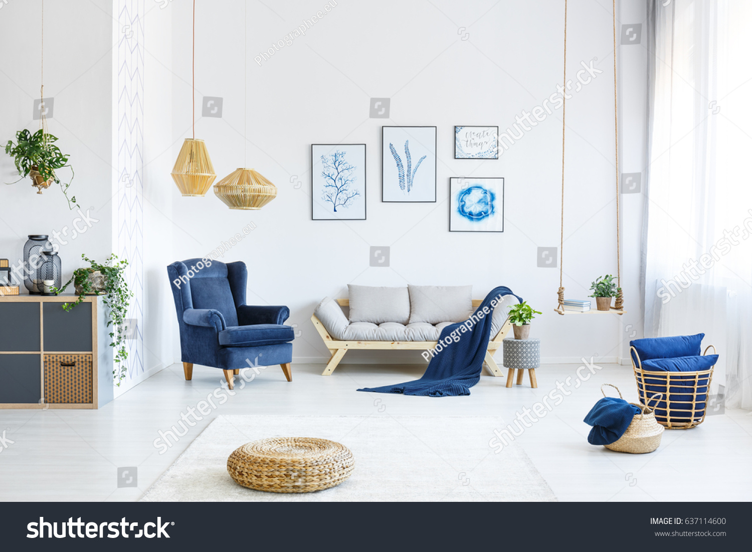 White living room with wood sofa, blue armchair, lamps, posters #637114600