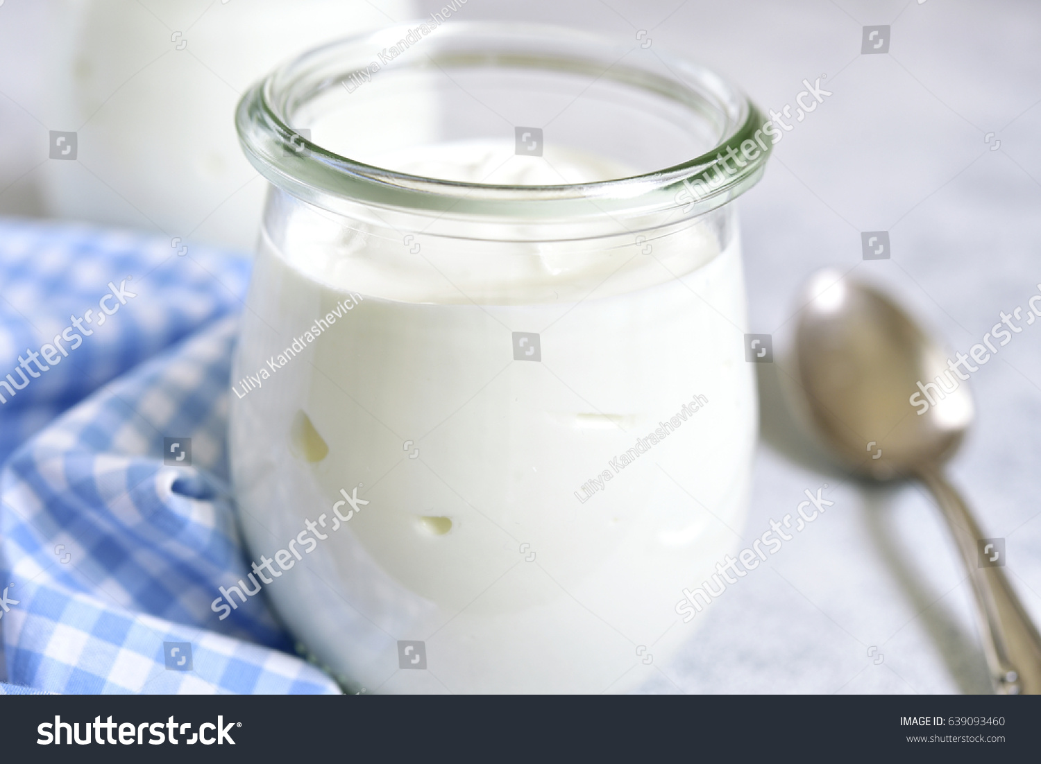 Two portions of fresh natural  homemade organic yogurt in a glass jar on a light slate background. #639093460