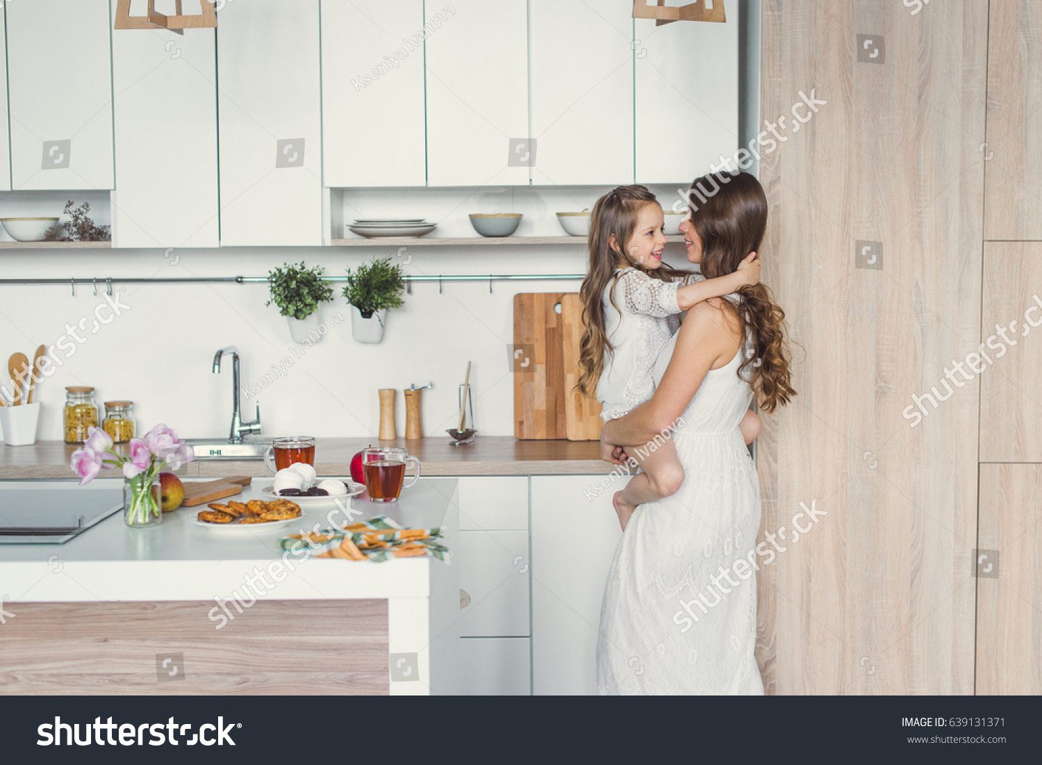 Mom and daughter in the kitchen. Daughter hugging mother on the kitchen. #639131371
