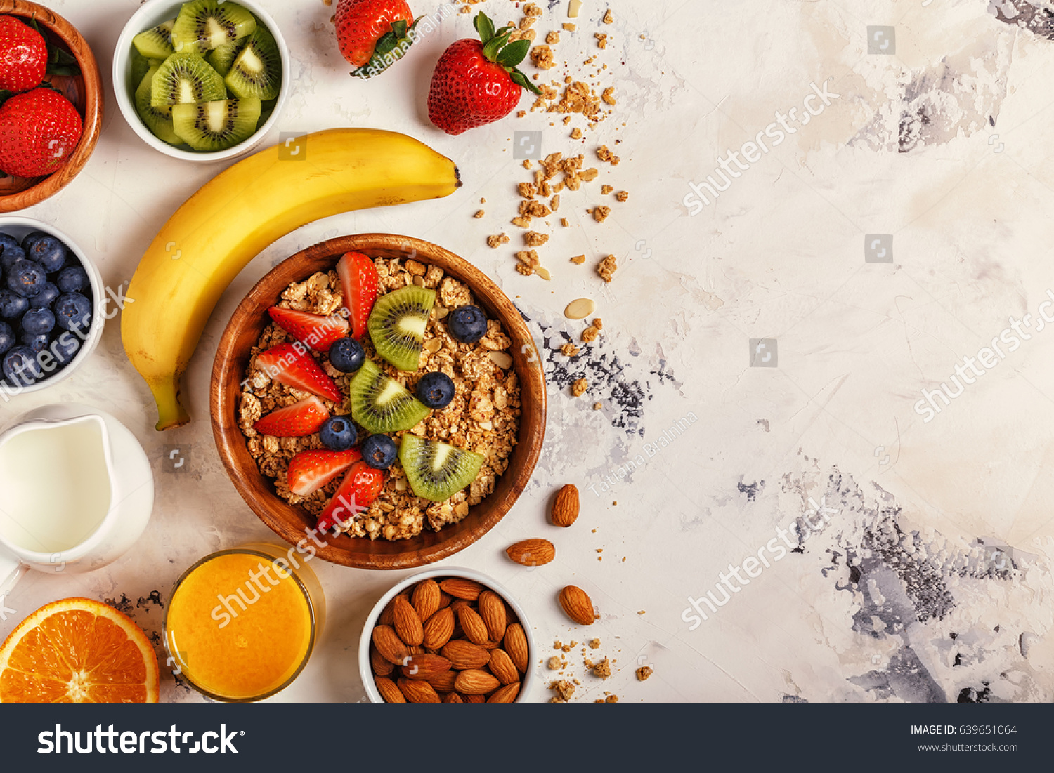 Healthy breakfast - bowl of muesli, berries and fruit, nuts, orange juice, milk, top view. #639651064